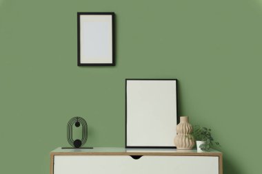 Yeşil duvarın yanındaki boş çerçeveli çekmeceler.