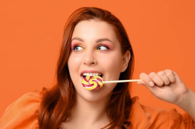 Renkli arka planda lezzetli lolipop yiyen güzel genç kadın, yakın plan.