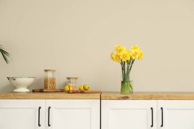 Mutfağın içinde bir buket nergis olan bir vazo.