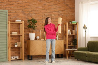 Happy young woman with gift fitness mat at home