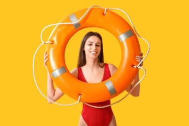 Yüzünde güneş kremi ve sarı arka planda can simidi olan güzel genç bir kadın.