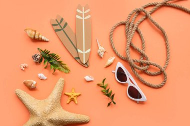 Renkli arka planda şık güneş gözlükleri, mini sörf tahtaları, ip ve deniz kabukları olan kompozisyon