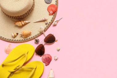Şık plaj aksesuarları ve pembe arka planda farklı deniz kabukları olan kompozisyon