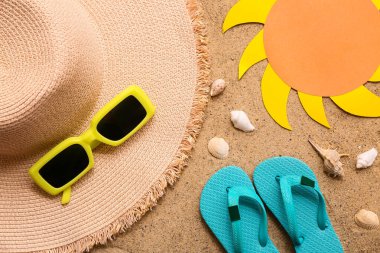 Şık plaj aksesuarları kağıt güneş ve kumdaki deniz kabukları.