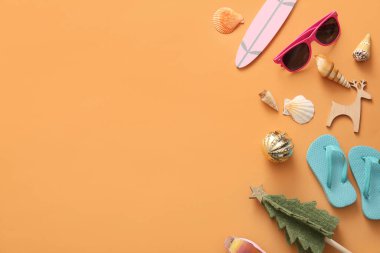 Plaj aksesuarları, deniz kabukları ve renk arka planında Noel dekoru olan kompozisyon