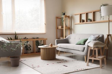 Gri kanepesi, raf ünitesi, sehpası ve lambası olan güzel bir oturma odası.