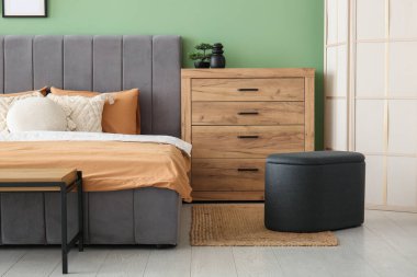 Rahat yatak, yastıklar ve şık yatak odasında ahşap çekmeceler.