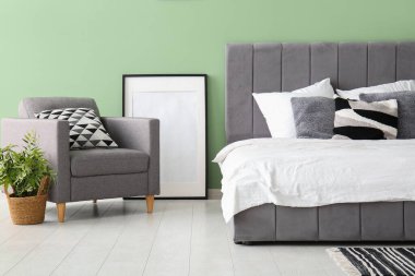 Rahat yatak, resim çerçevesi ve şık bir yatak odasında koltuk.