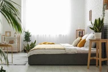 Şık bir yatak, güzel bir yatak odasında çiçekler ve kahve masası.