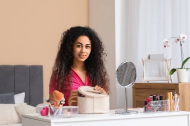 Güzel, mutlu, Afro-Amerikan bir kadın. Depoda makyaj yapıyor.