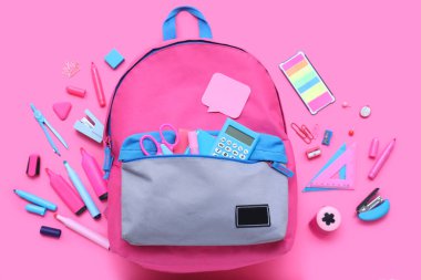 Şık okul çantalı kompozisyon ve pembe arka planda farklı kırtasiye malzemesi.