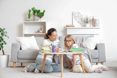 Gözlüklü küçük kız evde öğretmeniyle ders çalışıyor.