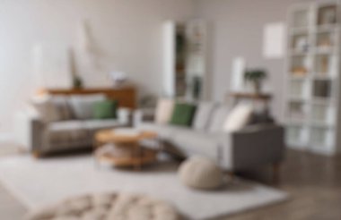 Gri kanepeler, masa ve raf üniteleriyle modern oturma odasının bulanık görüntüsü