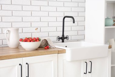 Mutfakta lavabonun yanında lezzetli çilek ve sepet.