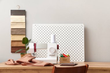 Ahşap masa üzerinde terzi malzemeleri olan modern dikiş makinesi.