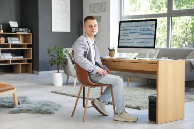 Modern ofis bilgisayarında çalışan genç bir erkek programcı.