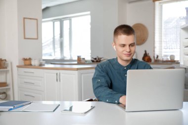 Açık ev ofisinde dizüstü bilgisayarla çalışan genç bir serbest çalışan.