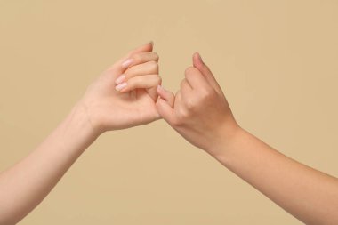 Renkli arka planda serçe parmak sözü veren kadınlar, yakın plan. Dostluk Günü kutlaması