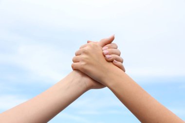 Gökyüzüne karşı el ele tutuşan kadınlar, yakın çekim. Dostluk Günü kutlaması
