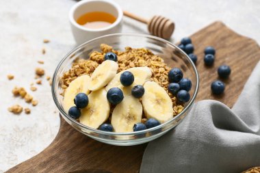 Peçete, tatlım, arkaplanda lezzetli granola, muz ve böğürtlenli kase, yakın plan.