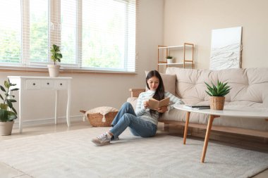 Kitap okuma ve evde katta oturan güzel genç kadın