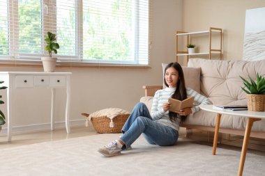 Kitap okuma ve evde katta oturan güzel genç kadın