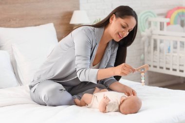 Güzel, genç, mutlu bir kadın bebeğiyle evde oynuyor.