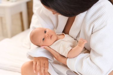 Evinde bebeğiyle bornozlu güzel bir kadın, yakın plan.