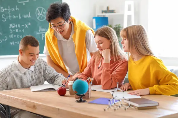 Tekerlekli sandalyede çocuğu olan bir grup genç öğrenci okulda çalışıyor.