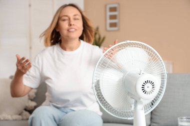 Evinde elektrikli yelpazesi olan güzel, olgun, mutlu bir kadın.