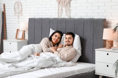 Uyanmış genç bir çift evde yatakta yatıyor.