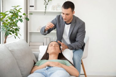 Psikolog muayenehanesinde hipnoz seansı sırasında kanepede yatan genç bir kadın.