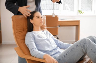 Ofiste genç bir kadını hipnotize eden sarkacı olan erkek psikolog.