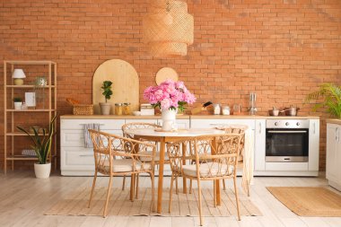 Mutfaktaki yemek masasında şakayık çiçekli vazo.