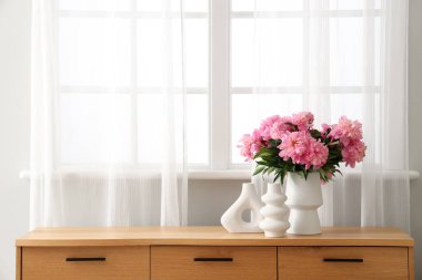 Bir buket pembe şakayık çiçekleri şık oturma odasındaki çekmecelerin üstünde, yakın plan.