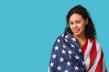 Mavi arka planda Amerikan bayrağı olan güzel, mutlu, Afro-Amerikan bir kadın.