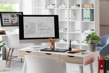 Ofiste bilgisayar ve kumaş örnekleriyle grafiksel tasarımcının çalışma yeri