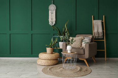 Çiçek, koltuk ve okaliptüs vazosu güzel odadaki sehpanın üzerinde.