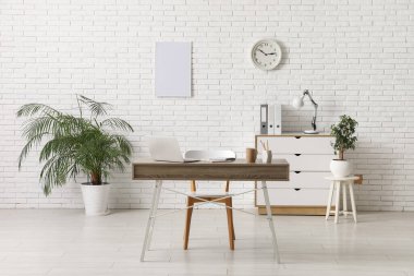 Çalışma yeri, dizüstü bilgisayarı, sandalyesi ve çekmeceleri olan şık bir ofis.