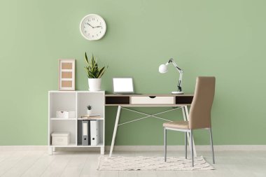 Çalışma yeri, dizüstü bilgisayarı, lambası ve raf ünitesi olan şık bir ofis.