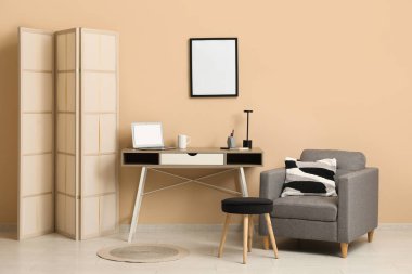 Çalışma odası, katlanan ekran, koltuk ve sehpası olan şık bir ofis.