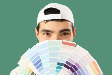 Male painter with color palettes on green background, closeup