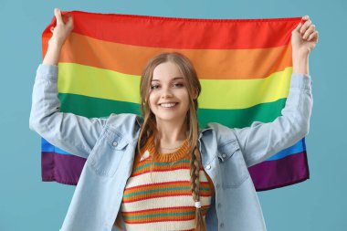 Beautiful young woman with LGBT flag on blue background