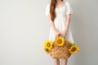Hasır sepette güzel ayçiçekleri olan genç bir kadın.