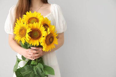 Açık arkaplanda güzel ayçiçekleri olan genç bir kadın.