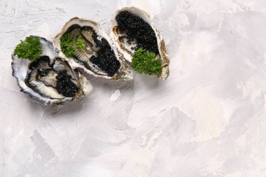 Gri arka planda siyah havyarlı lezzetli istiridyeler.