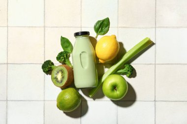 Taze sebzeli bir şişe lezzetli meyve suyu ve beyaz fayanslı meyveler.