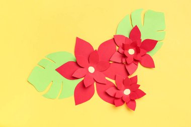 Sarı arka planda yaprakları olan kırmızı origami çiçekleri
