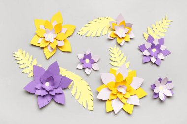 Gri arkaplanda yaprakları olan renkli origami çiçekleri