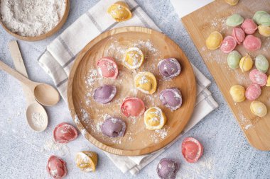 Beyaz arka planda renkli çiğ hamur köfteleri olan ahşap tabak ve yemek.